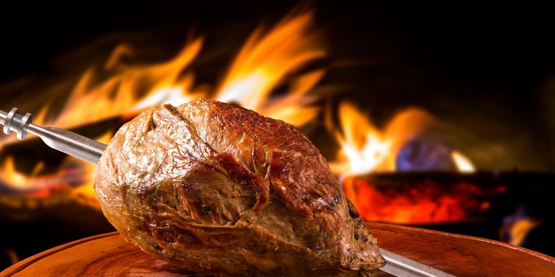 Cupim assado no espeto com fundo de churrasqueira, pronto para ser servido na Ramalho Experience em Campinas