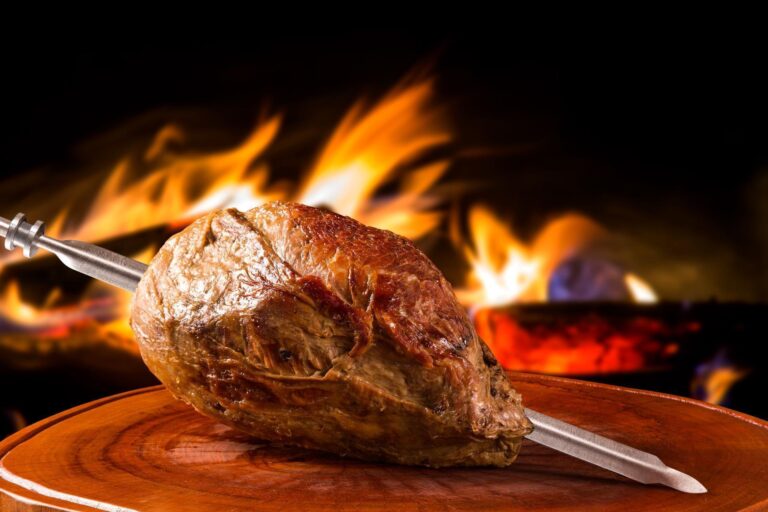 Cupim assado no espeto com fundo de churrasqueira, pronto para ser servido na Ramalho Experience em Campinas