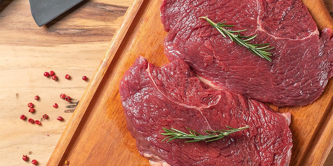 Baby Beef Campinas – Qualidade Premium Ramalho Carnes Quatro fatias frescas e suculentas de baby beef campinas dispostas sobre uma tábua de madeira artesanal na Ramalho Carnes.