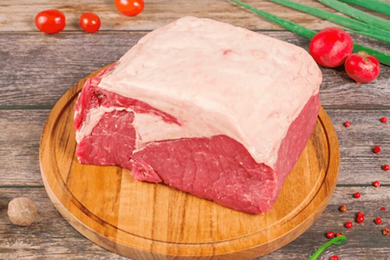 Bife de Chorizo: O Corte Definitivo de Carne para Churrasco com Gordura Uma peça de bife de chorizo cru com uma espessa capa de gordura sobre uma tábua de madeira rústica, cercada por ingredientes frescos como tomate, cebolinha, pimenta, pimenta e noz-moscada.