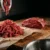 Qual a melhor carne moída: patinho moído saindo do moedor ao lado da peça inteira no balcão do açougue
